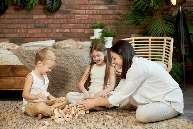 Maman et les enfants jouent à la tour de squirl. Femme fille et garçon jouent au jeu de puzzle familial. Journée en famille