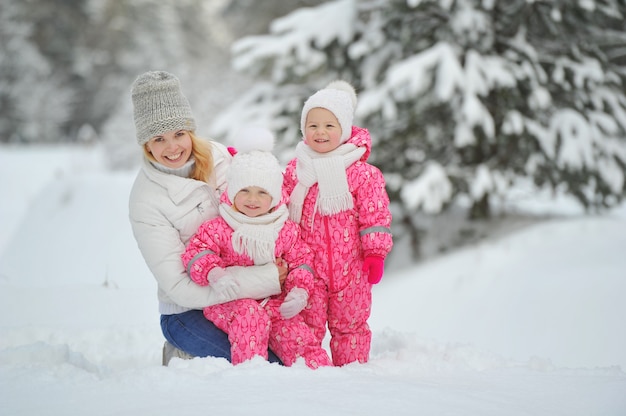 Maman et enfants en promenade en hiver dans la forêt.