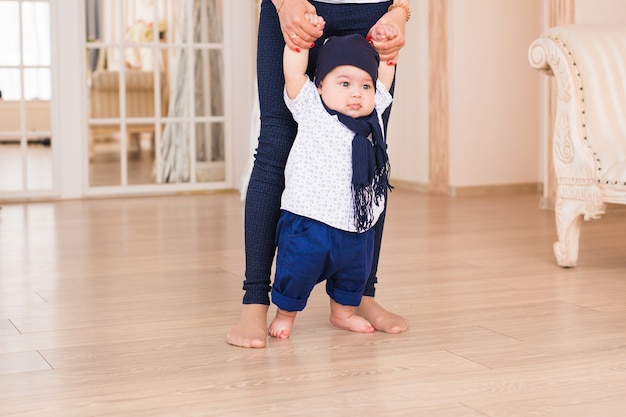 Maman enseigne les premiers pas de son fils à l'intérieur.