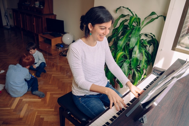 Maman essaie de jouer du piano à la maison tout en s'occupant d'enfants méchants que veut jouer.