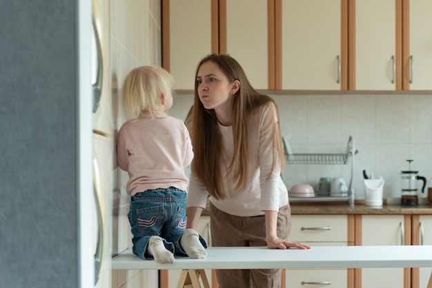 Maman est en colère contre le petit enfant debout dans la cuisine.