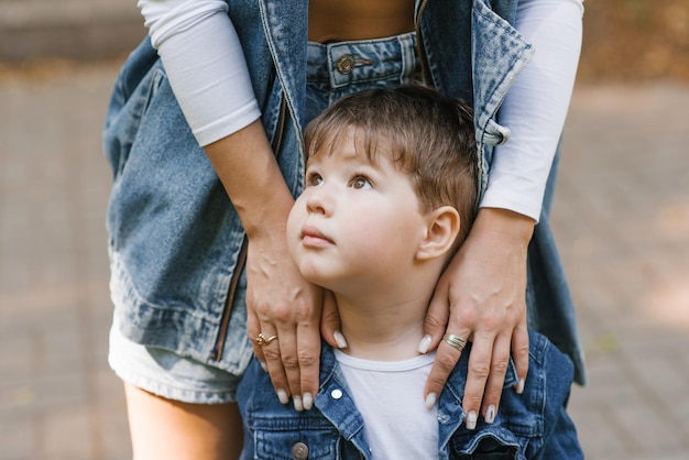 Maman étreint son fils curieux par les épaules