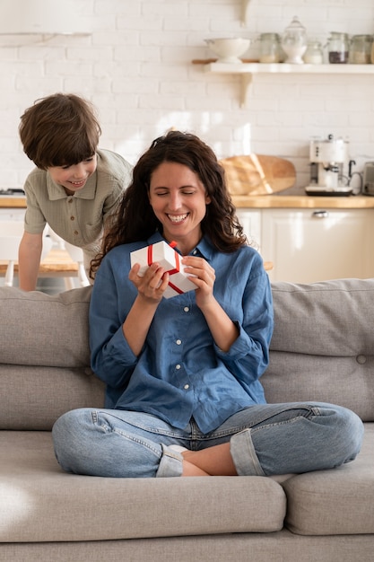 Maman excitée tient le cadeau d'anniversaire d'un petit garçon félicitant maman le jour de la fête des mères avec un cadeau