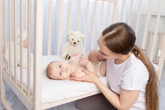 Maman fait dormir bébé dans le berceau ou lui donne un rongeur, une famille heureuse.