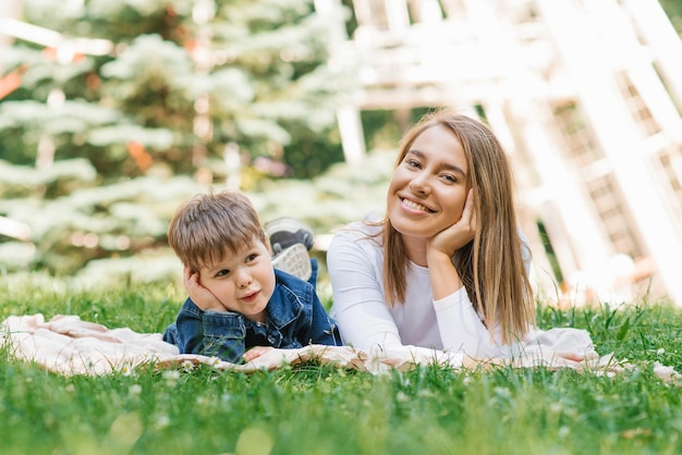 Maman de famille et son fils s'allongent sur l'herbe dans le parc en été et se détendent