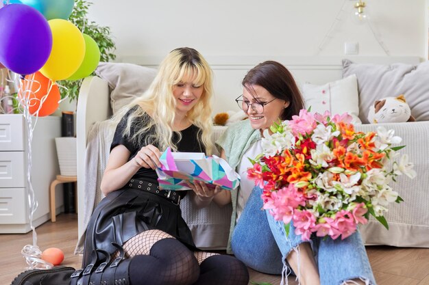 Maman félicitant sa fille avec un bouquet de fleurs et une boîte-cadeau surprise