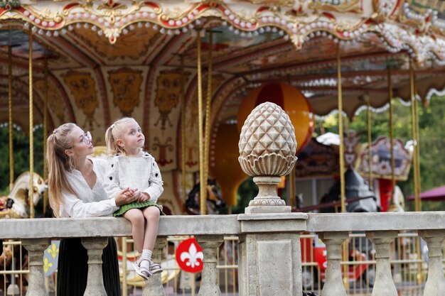 Maman et fille au parc d'attractions en été sur une promenade