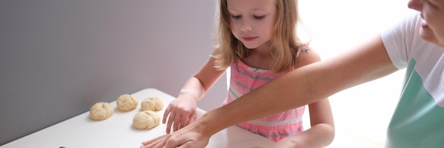 Maman et fille déployant la pâte à farine à table dans la cuisine