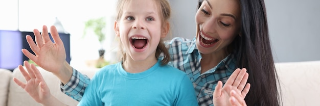 Une maman et une fille enthousiastes avec une boîte-cadeau sont assises sur un canapé