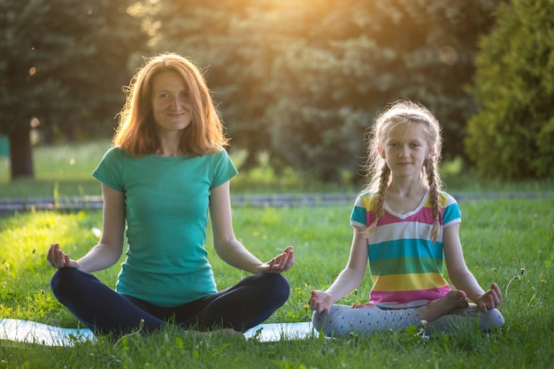 maman et fille faisant du yoga dans le parc