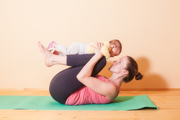 Maman et fille faisant des exercices de yoga sur tapis vert