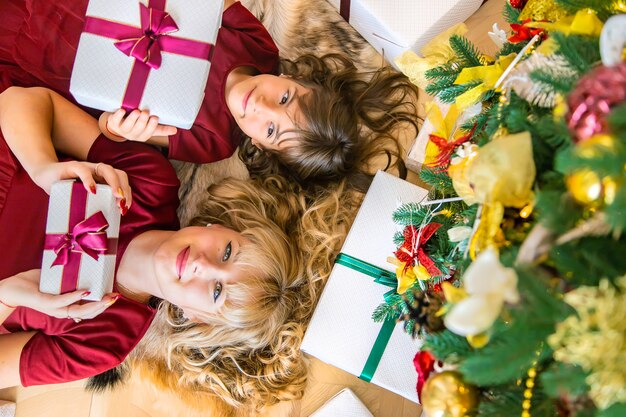 Maman avec une fille près de l'arbre de Noël avec des cadeaux.