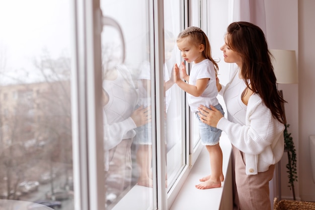 Maman et fille regardent par la fenêtre à l'extérieur