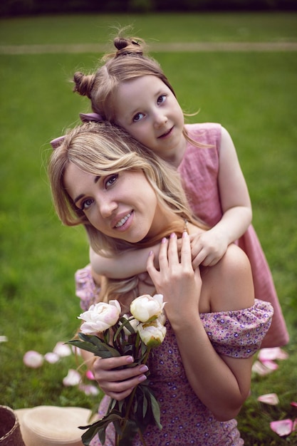 Photo maman et fille en robes roses assises sur un champ vert en été