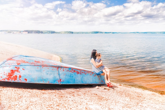 Maman et fille sont assises sur le vieux bateau sur le lac