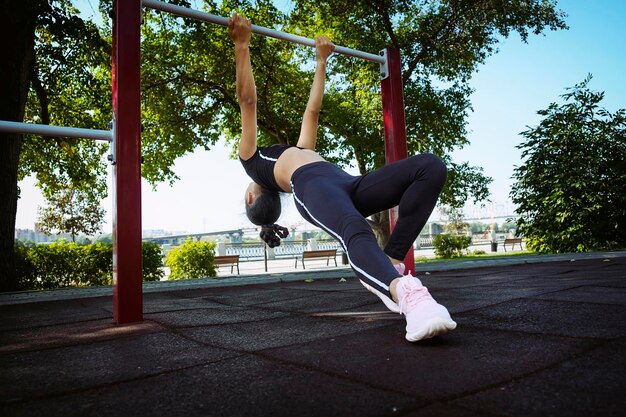 maman et fille en vêtements de sport par une journée d'été ensoleillée sur le talus dans le parc faisant du fitness