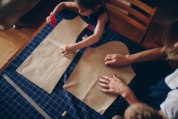 Maman et filles cousent des vêtements ensemble. Robe à motif.