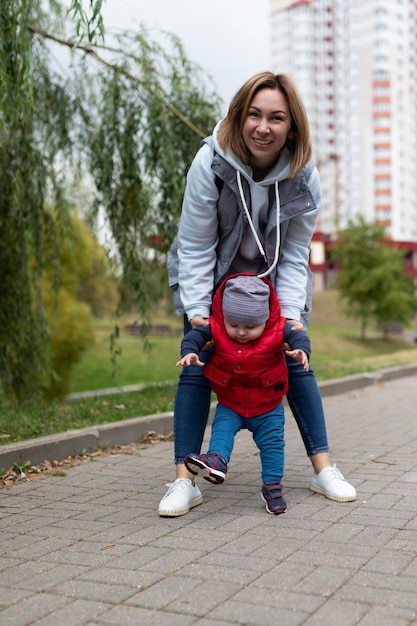 Maman avec un fils d'un an en promenade tenant ses mains