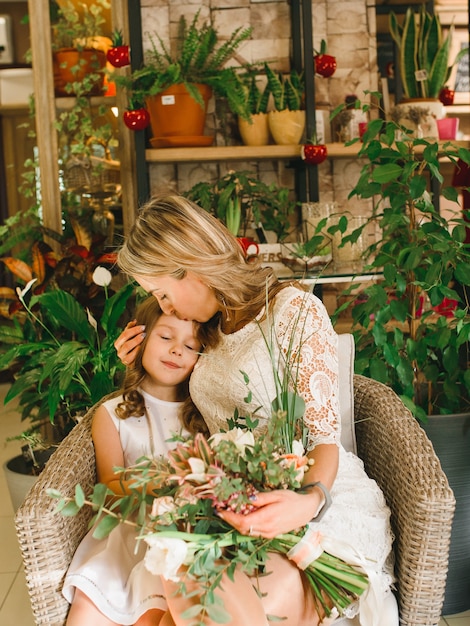 Maman et fils avec des fleurs au café. Fils donne des fleurs à la mère. jolie famille. Journée internationale de la femme, le 8 mars célébrant