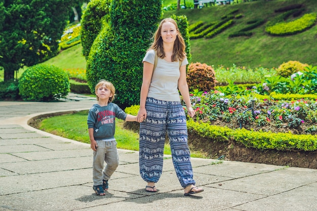 Maman et fils marchent dans le parc tropical