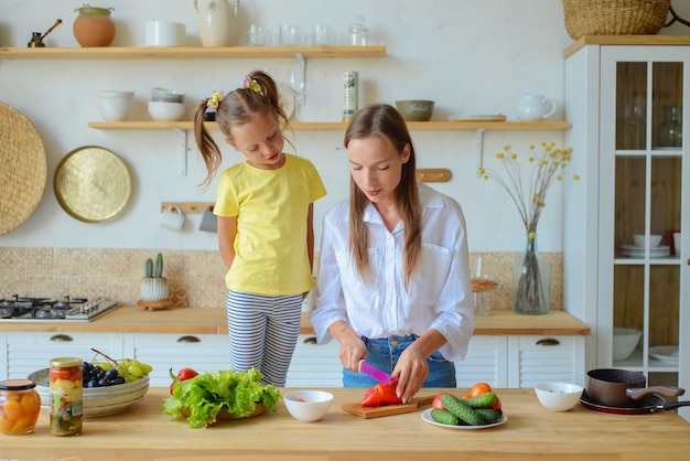 Une maman heureuse apprend à sa petite fille à cuisiner des aliments sains maman et fille parlant en souriant