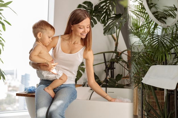 La maman heureuse va baigner son bébé