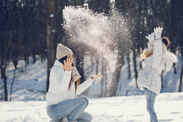 maman jeune et élégante, jouant avec sa petite fille mignonne dans le parc de neige de l&#39;hiver