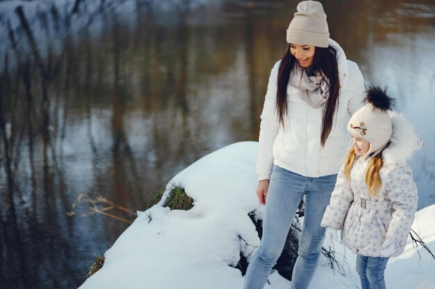 maman jeune et élégante, jouant avec sa petite fille mignonne dans le parc de neige de l&#39;hiver