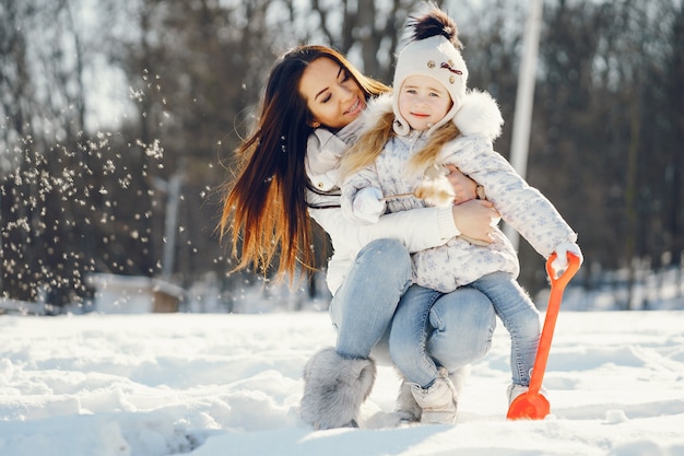 maman jeune et élégante, jouant avec sa petite fille mignonne dans le parc de neige de l&#39;hiver