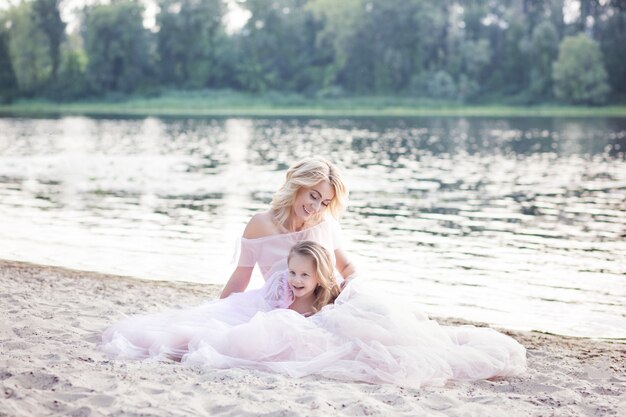 Maman joue avec son enfant en vacances au bord du lac. Mode de vie familial et concept d'amour. Mère et fille ayant des moments tendres à l'extérieur. Famille mignonne près de l'eau. Famille aimante heureuse.