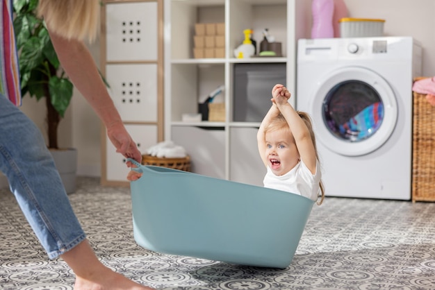 Une maman joyeuse joue avec son bébé dans la buanderie petite blonde mignonne