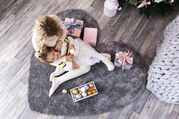 Maman joyeuse et sa fille mignonne s'amuser près de l'arbre de Noël à l'intérieur.