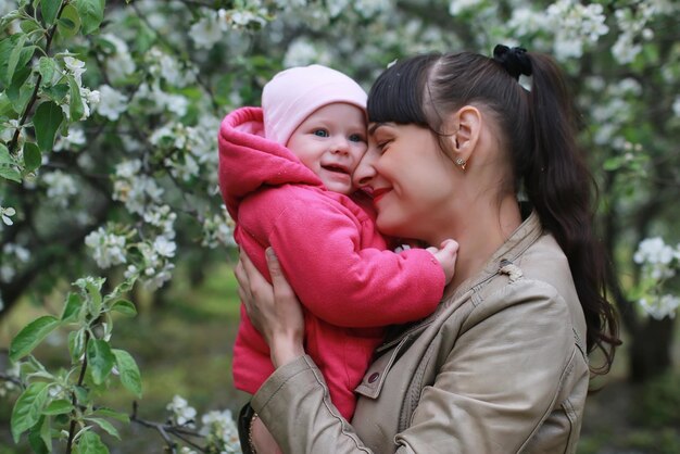 Maman avec des jumeaux sur un plaid en plein air dans un jardin de pommiers