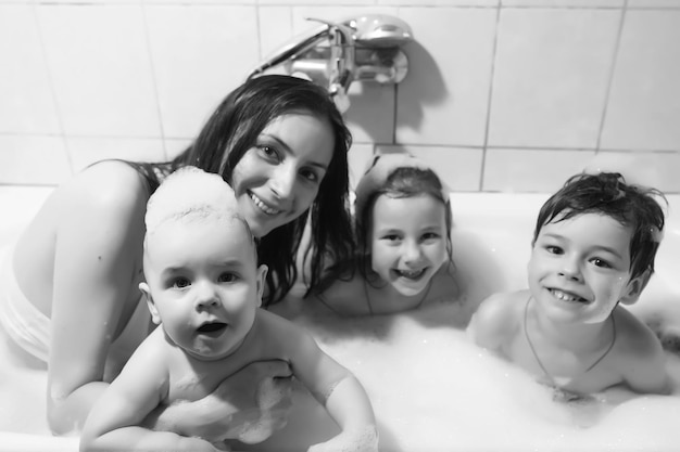 Maman lave les enfants. La maman et les enfants prennent des procédures d'eau dans la salle de bain. Mousse, pulvérisation.