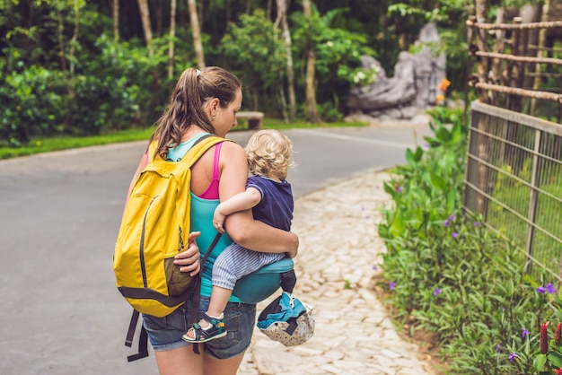 Maman marche avec un bébé dans le parc, à l'aide d'un siège de hanche