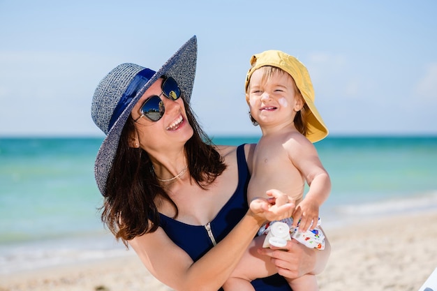 Maman a mis de la crème solaire sur les joues de bébé