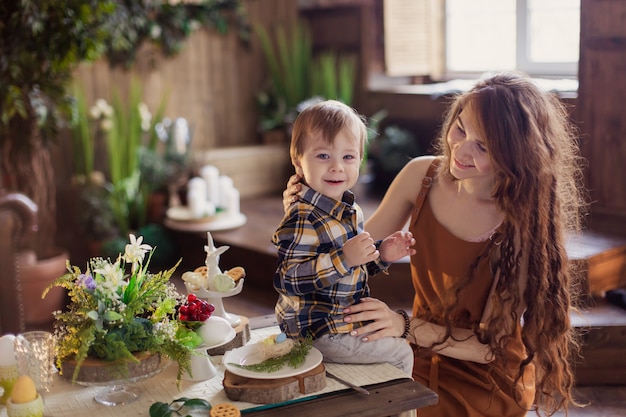 Maman montre le fils d'un petit poulet nouveau-né. Le garçon embrasse le poussin mignon avec tendresse et charme. Bambin dans une ferme à la campagne. Décoration de table de Pâques concept célébration oeufs. Printemps nature eco veg