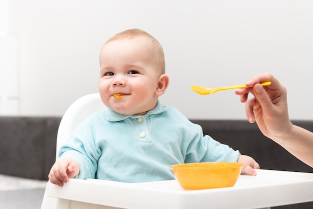 Maman nourrit bébé avec de la purée de fruits à la maison