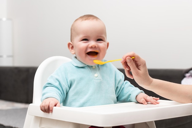 Maman nourrit bébé avec de la purée de fruits à la maison