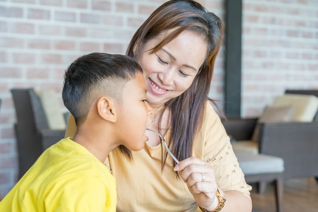 Maman nourrit son fils avec un sourire.