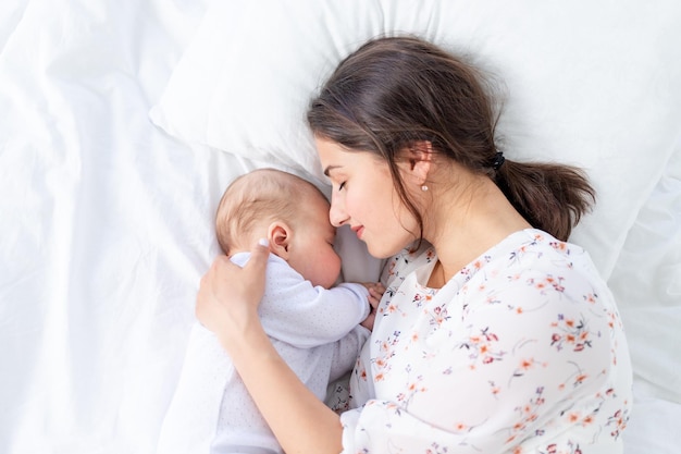 Maman et nouveau-né dorment ensemble maman met bébé à dormir sur le lit dans la chambre le concept de maternité et de sommeil sain