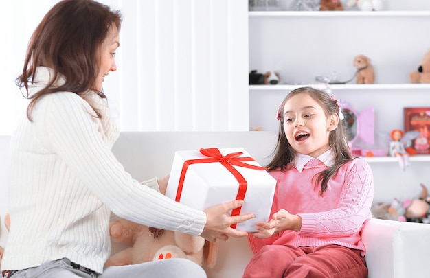 Maman offre à sa fille une boîte avec un cadeau d'anniversaire.