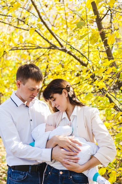 Maman et papa avec un bébé, un petit garçon marchant à l'automne dans le parc ou la forêt. Feuilles jaunes, la beauté de la nature. Communication entre un enfant et un parent.