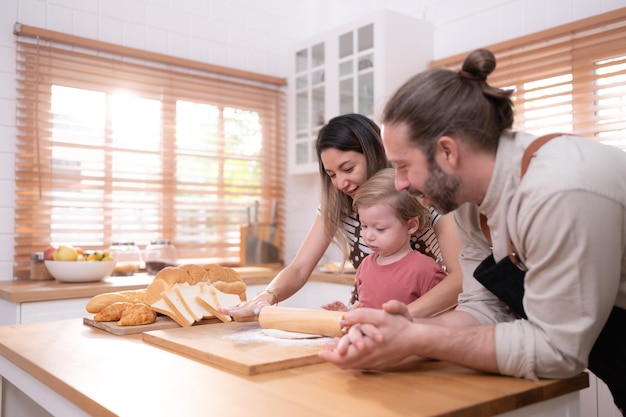 Maman et papa dans la cuisine de la maison avec leurs petits enfants s'amusent à cuisiner du pain