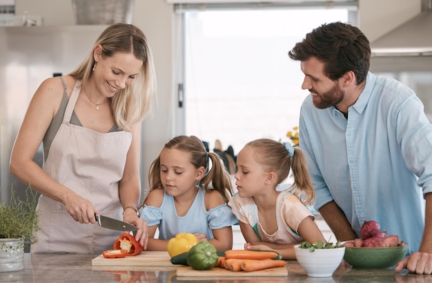 Maman papa et enfants cuisinant dans la cuisine avec des légumes pour la nutrition déjeuner sain et régime végétalien Nourriture familiale et parents avec des filles apprenant à enseigner et à aider à couper les ingrédients pour la préparation des repas