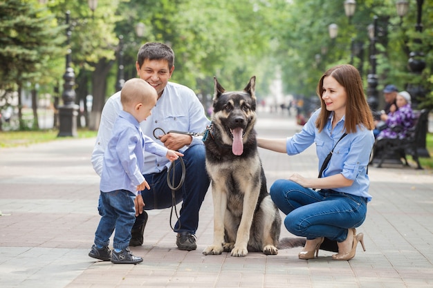 Maman, papa et fils en promenade avec un chien de berger sur la ville