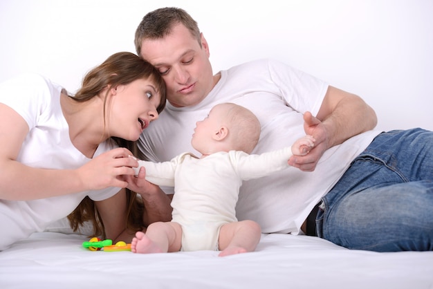 Maman et papa avec un petit enfant sur le lit.