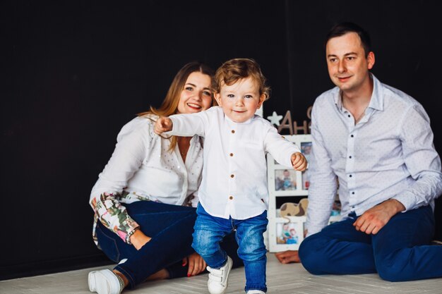 Maman et papa s&#39;amusent avec leur petit fils charmant posant dans un studio confortable