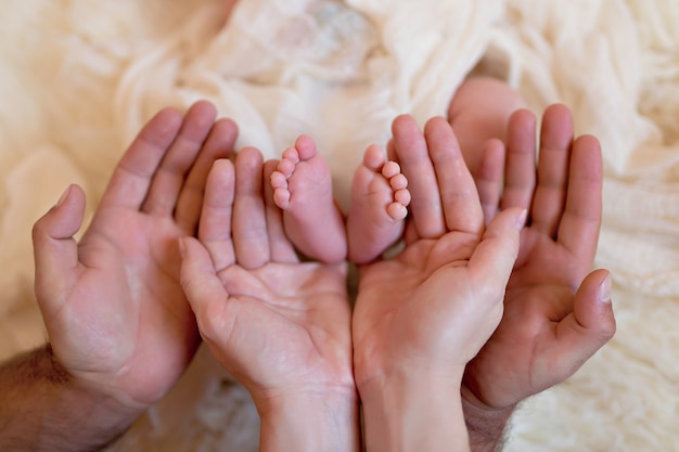 Maman et papa tiennent les pieds d'un nouveau-né