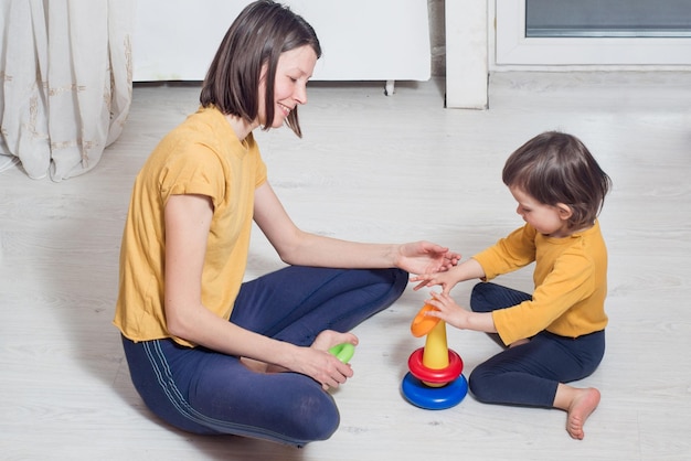 Maman et un petit enfant jouent ensemble sur le sol avec des jouets